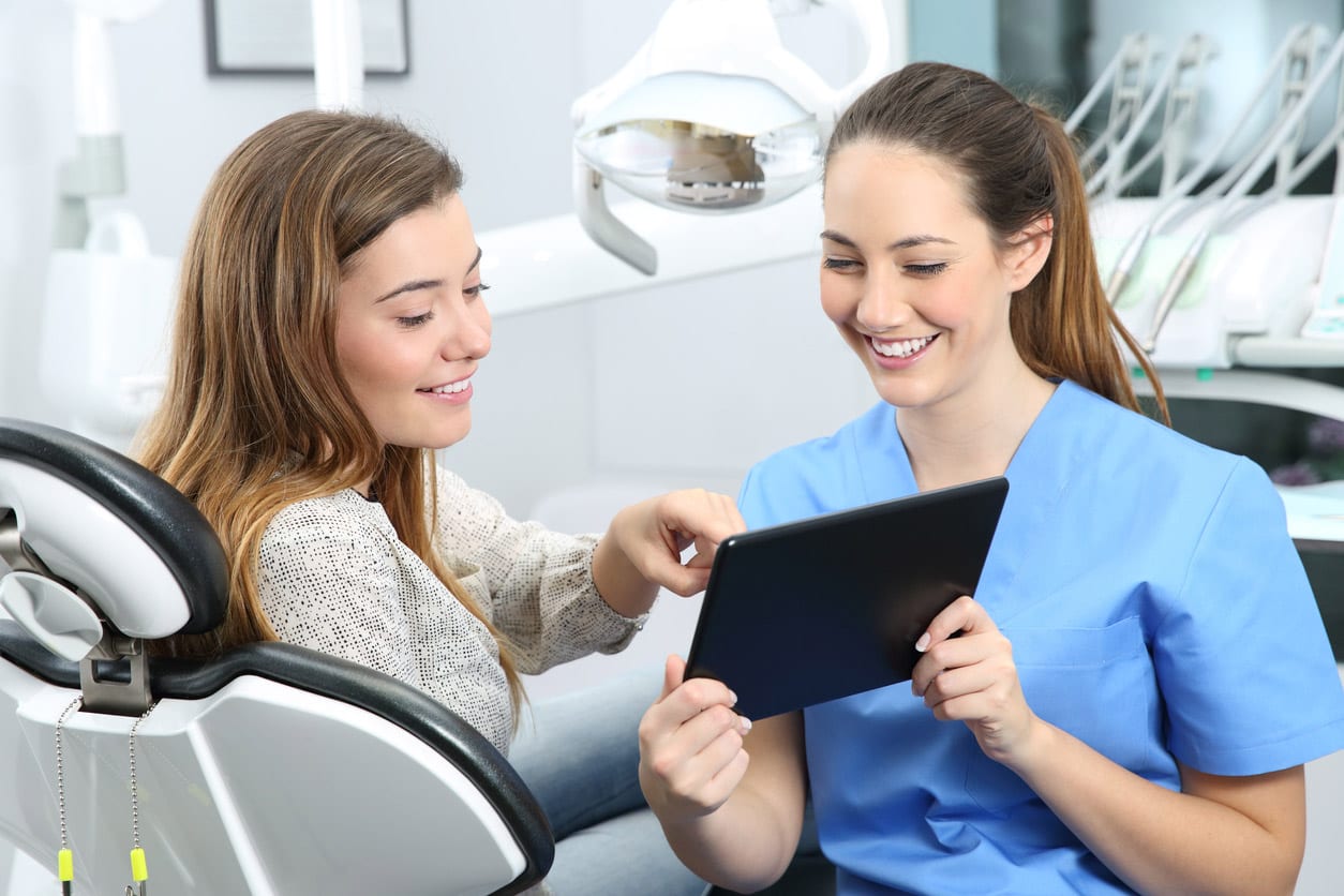 dental assistant and patient looking at tablet